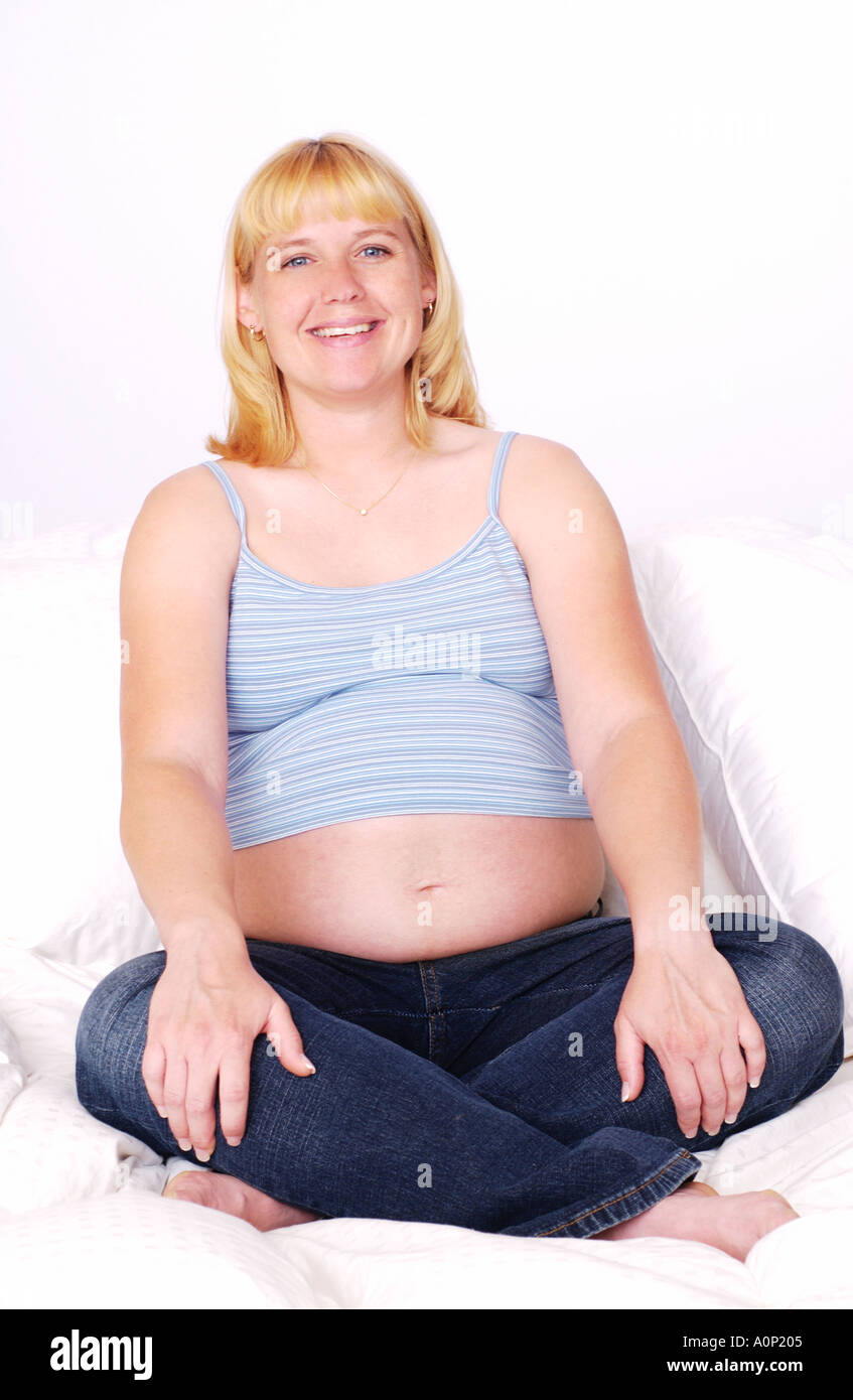 Pregnant woman sitting in bed smiling Stock Photo