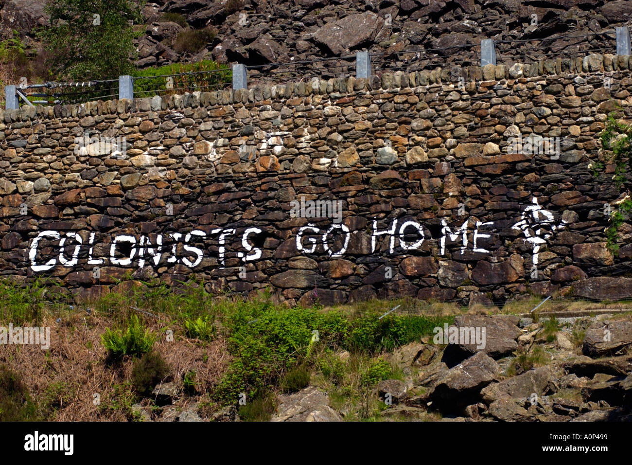 COLONISTS GO HOME Welsh extremist grafitti on roadside stone wall near Beddgelert Gwynedd North Wales UK Stock Photo