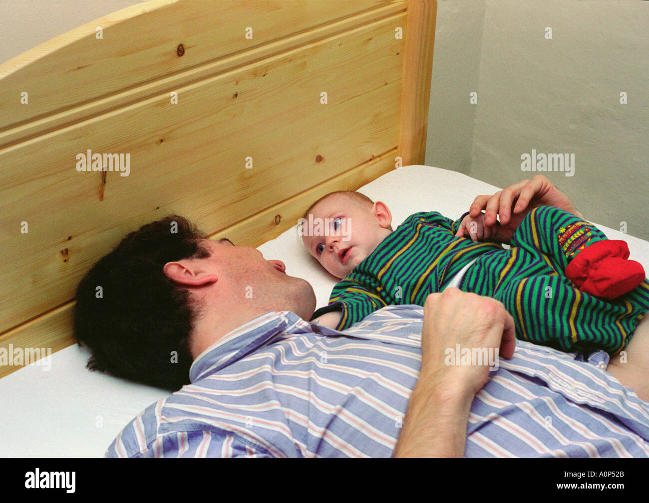 father lying next to baby on a bed Stock Photo - Alamy