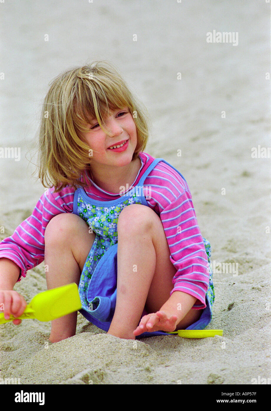 colourful image of child, smiling and playing in the sand at the beach Stock Photo