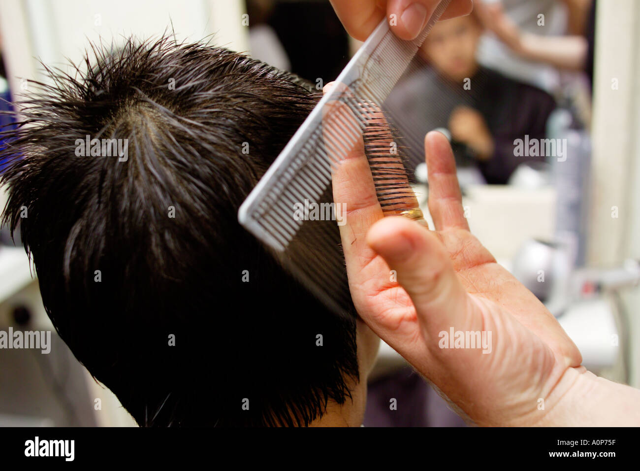 Teenage boy having his hair cut at a barbers in England Stock Photo