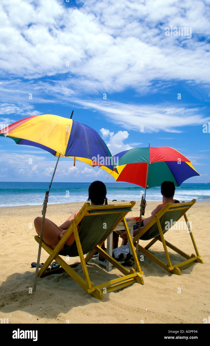 Couple sitting under colorful umbrellas Hikkaduwa beach Stock Photo