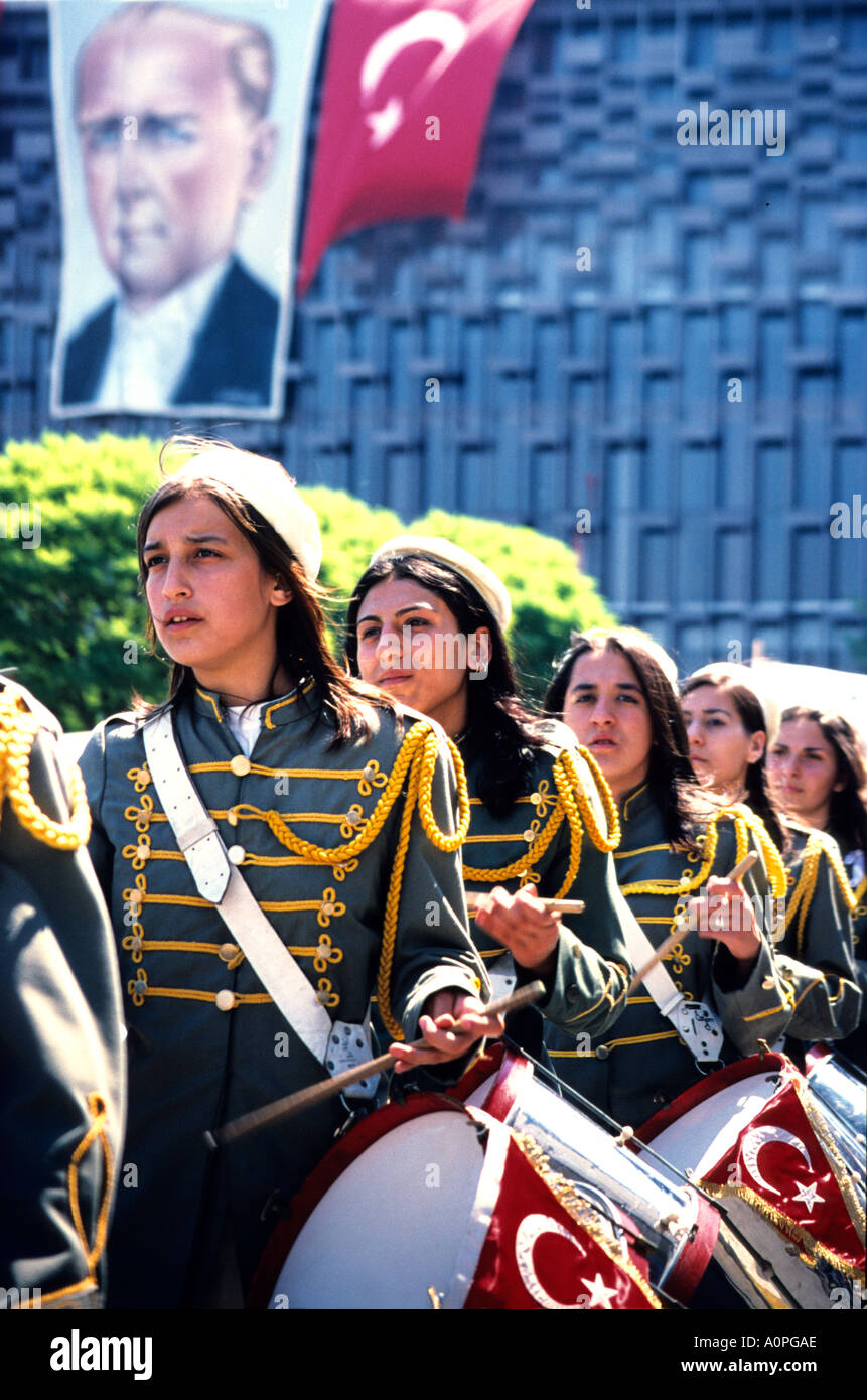 Young Turkish Women beating drums on a parade with poster of Kemal Atarturk looking down upon them - celebrating national youth day Stock Photo