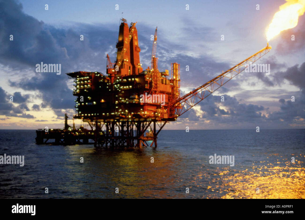Flaring off gases on the North West Hutton North Sea oil platform at sunset. Stock Photo
