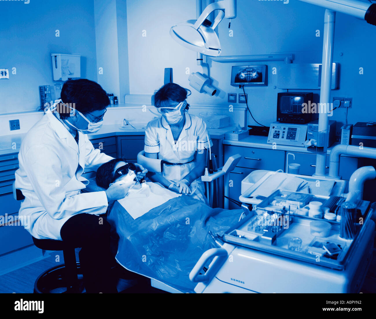 Dentistry. Dentist and dental nurse examining young boy's teeth Stock