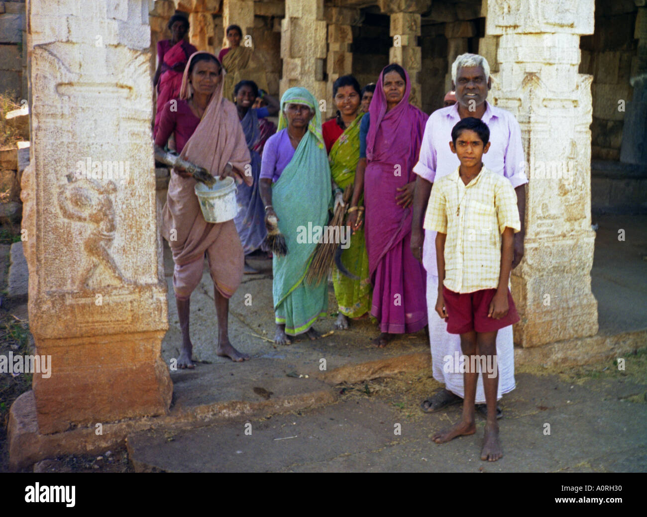 Group of women man & boy in colourful traditional clothing looking after ancient temples Hampi Karnataka India South Asia Stock Photo