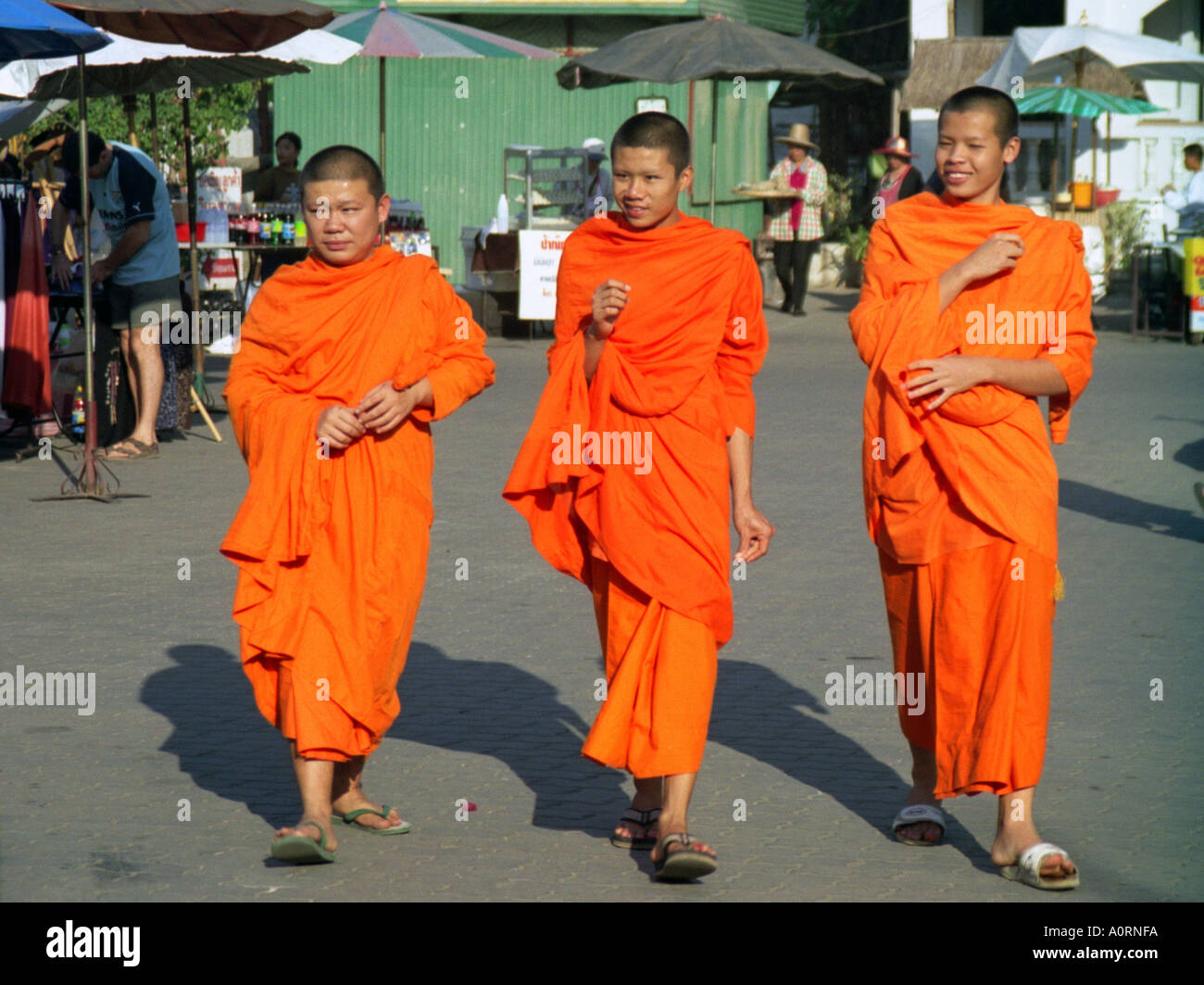 Group of young shaved head novices traditional colourful robe walk march together smile Khon Kaen Thailand Southeast Asia Stock Photo