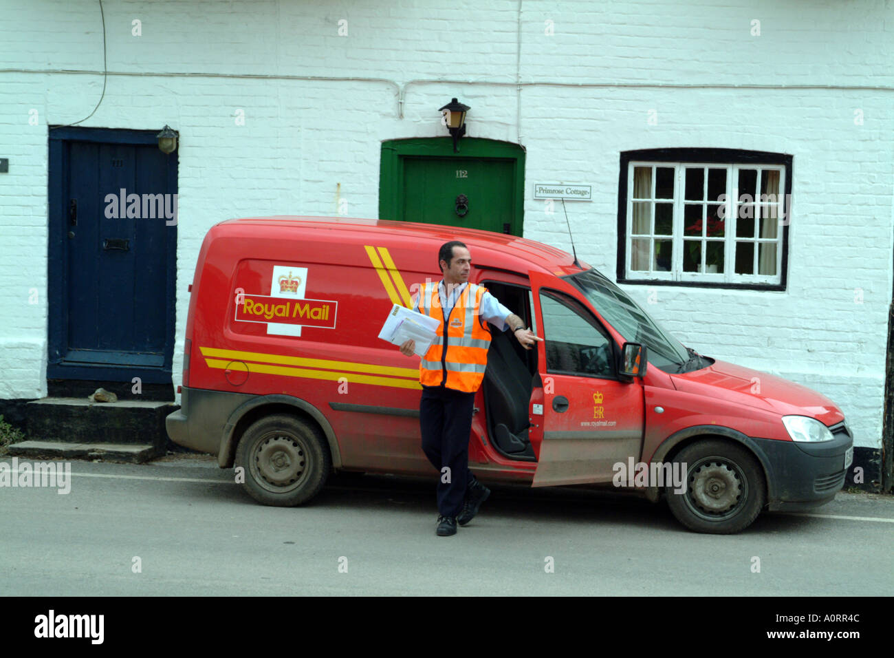 Postman delivers letters in rural location England UK Royal Mail Stock Photo