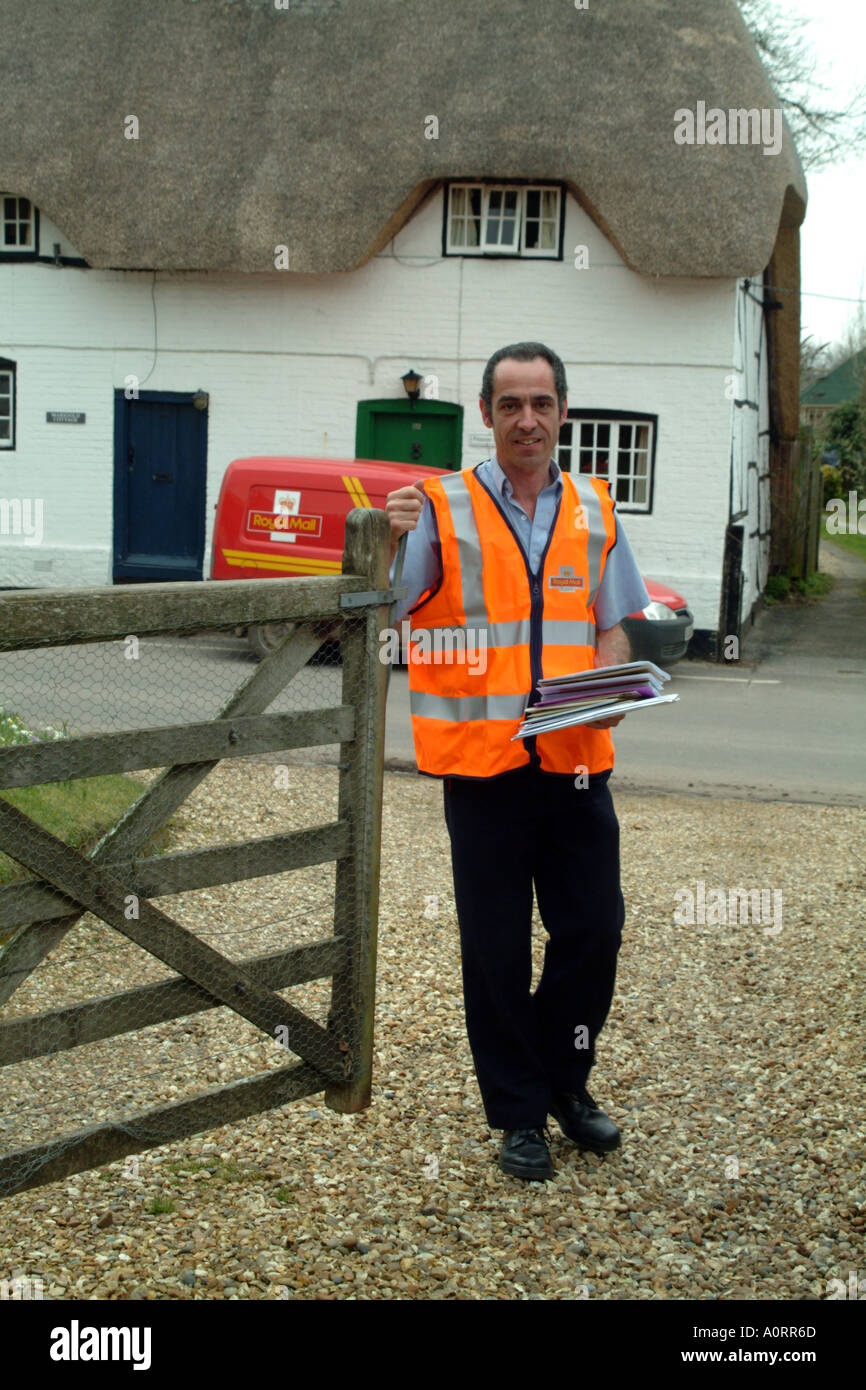 postman delivers letters in rural location England UK Royal Mail opens gate Stock Photo