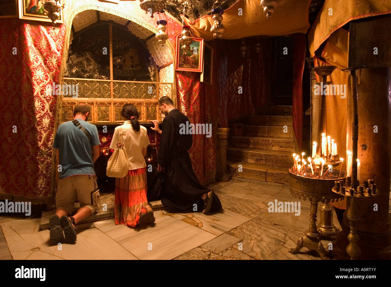 Priest and tourists praying in the Church of the Nativity birth place