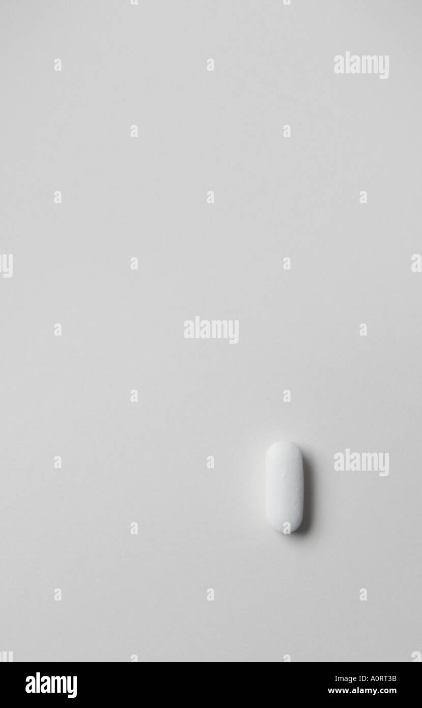 still life image of one pill with lots of space around it on whiteback ground looking down shot in the studio Stock Photo