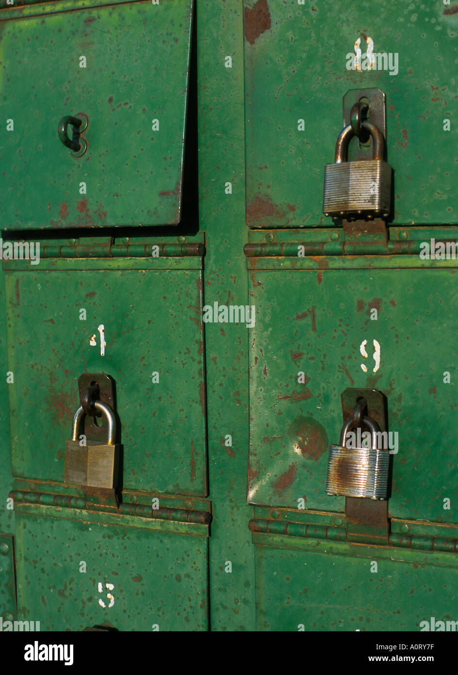 Weathered green mailboxes or compartments with numbers and padlocks and