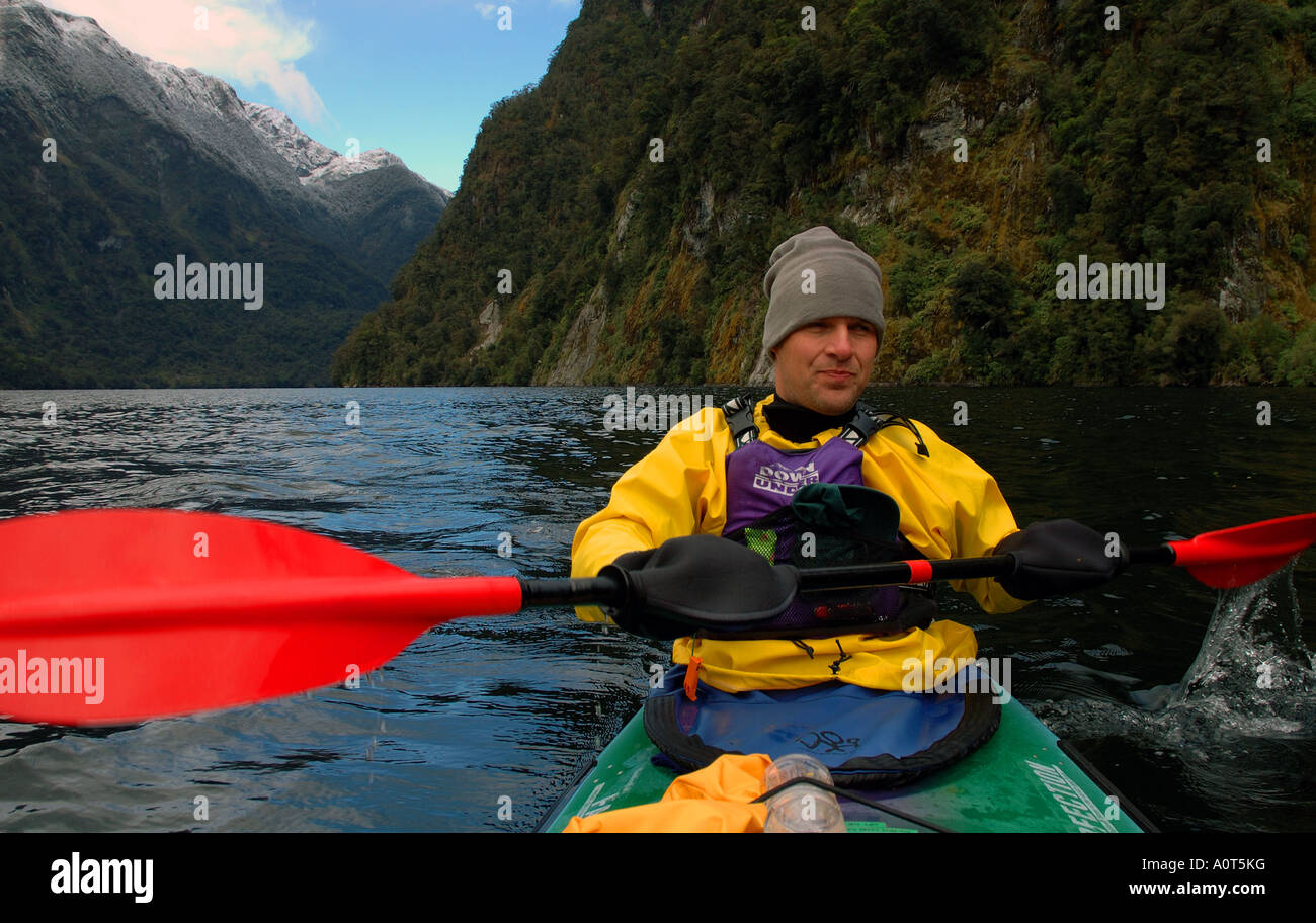 Man in cold climate gear paddling sea kayak in Doubtful Sound Fiordland