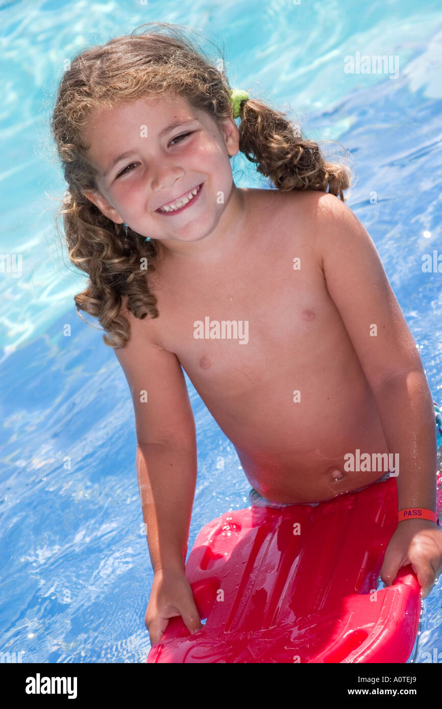 Happy little girl in the pool with red plastic board learning how to