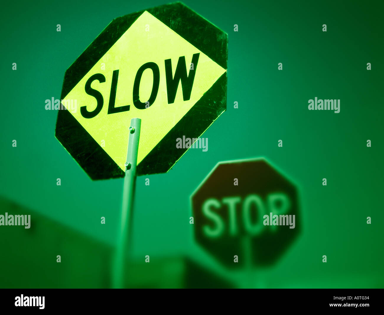 Sign with word SLOW on it and with an out of focus STOP sign in background Stock Photo