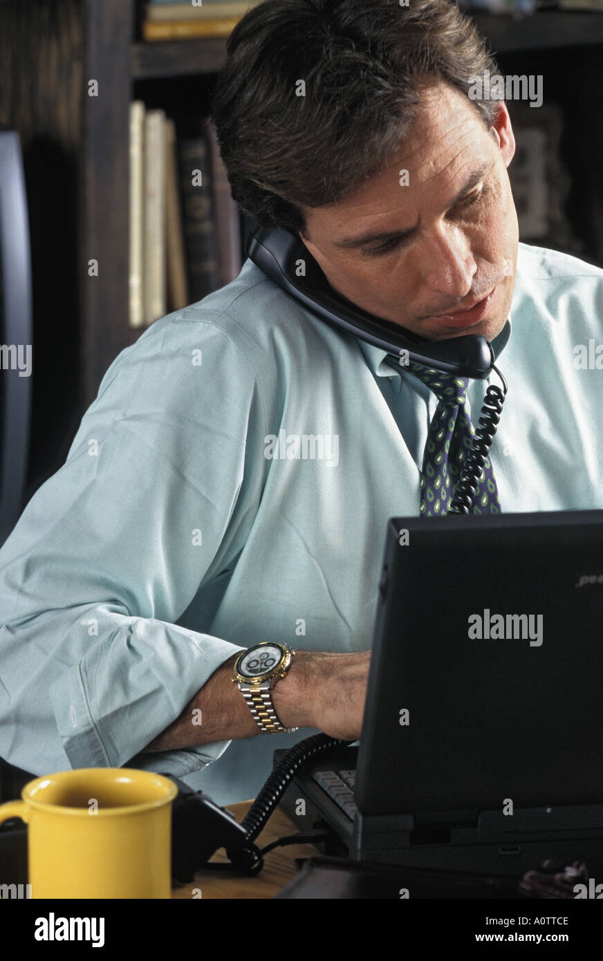 Caucasian businessman talking on phone working on laptop computer Stock Photo