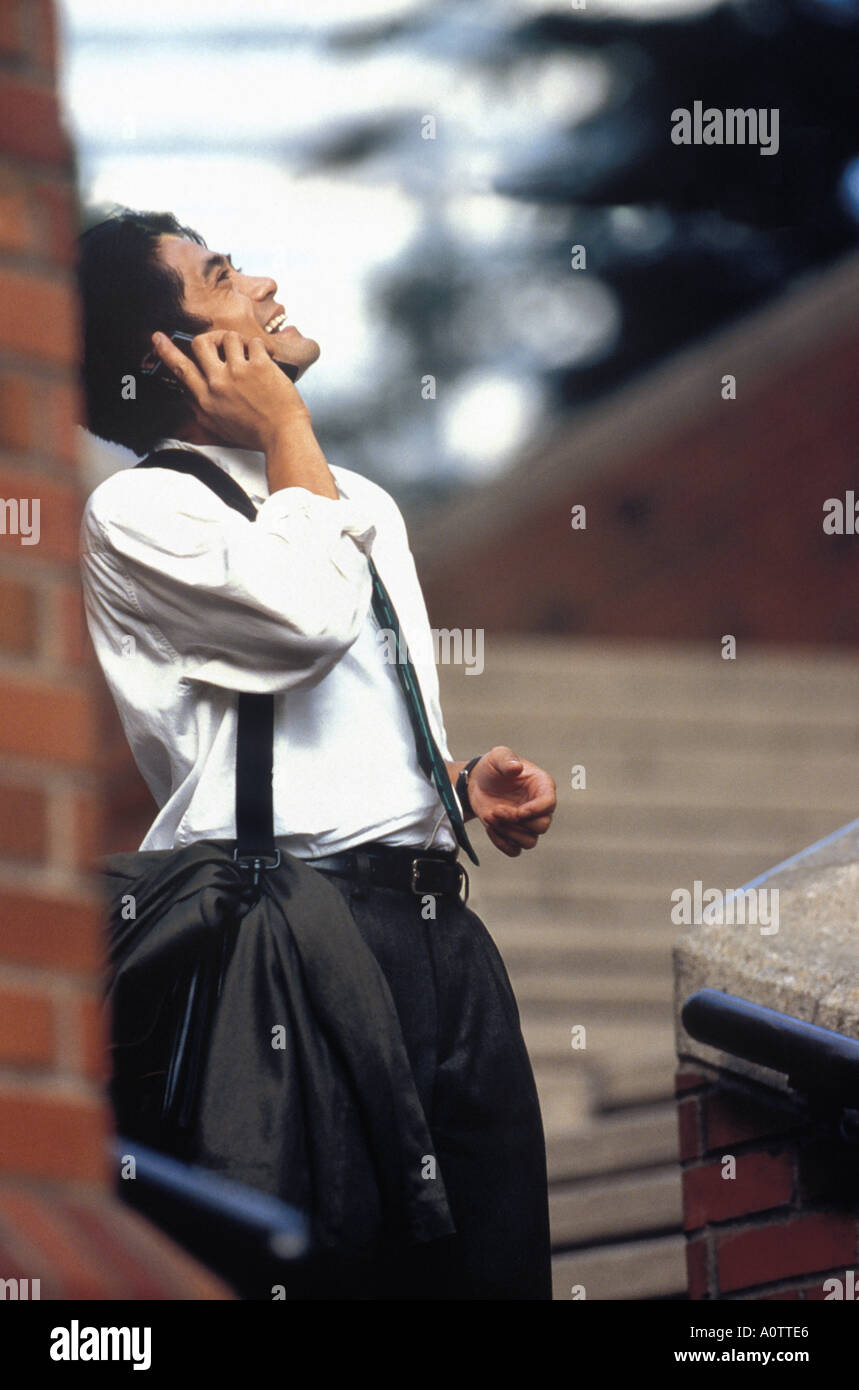 Asian American businessman Laughing and talking on mobile phone outdoors Stock Photo