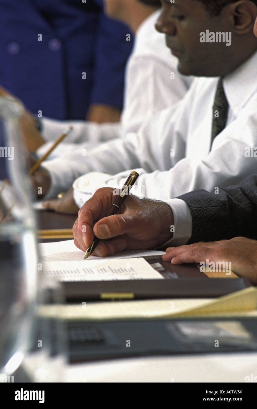 Closeup of an African American executive's hand making notes  while participating in a business meeting Stock Photo