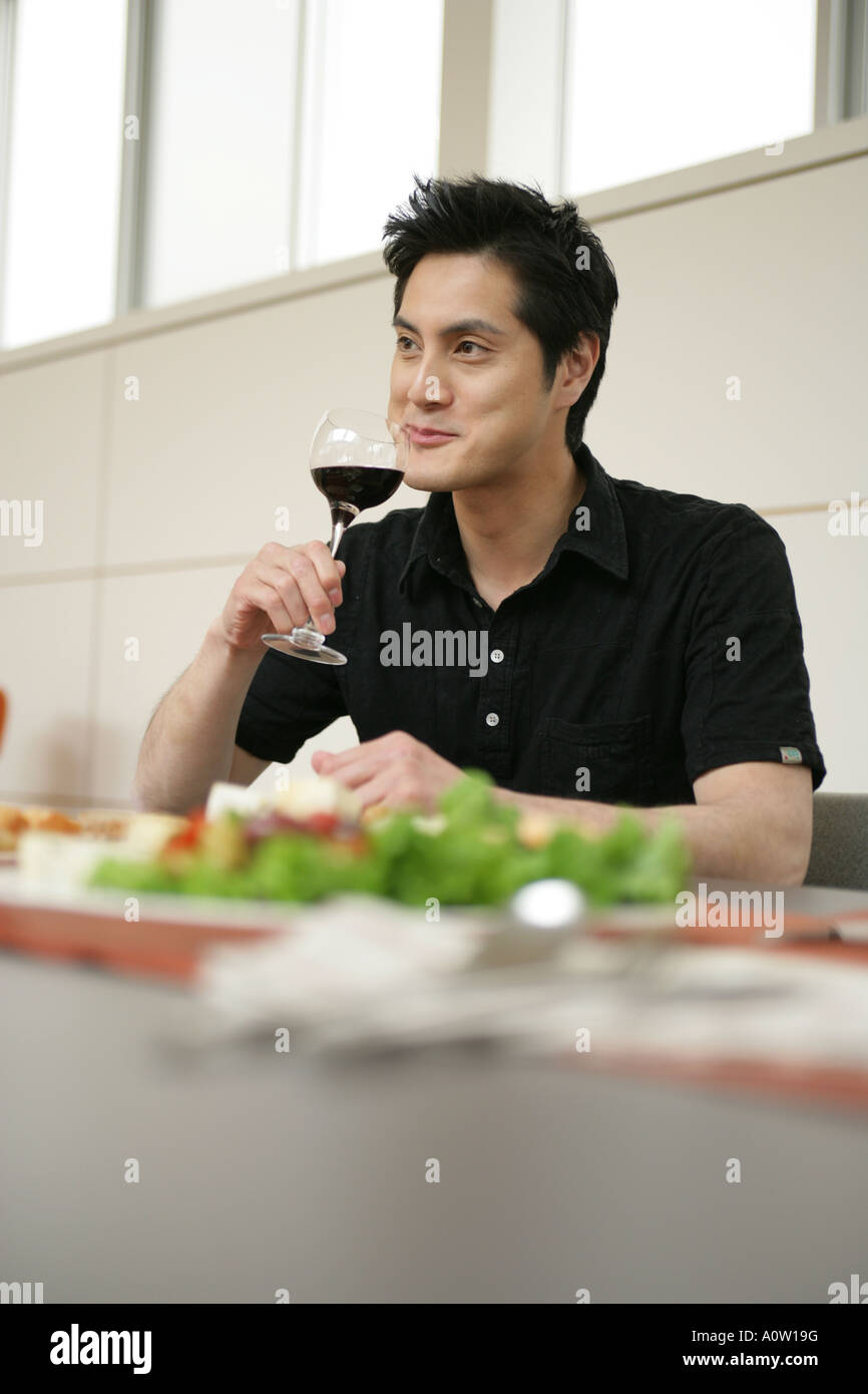 Young man drinking a glass of red wine at the dining table Stock Photo ...