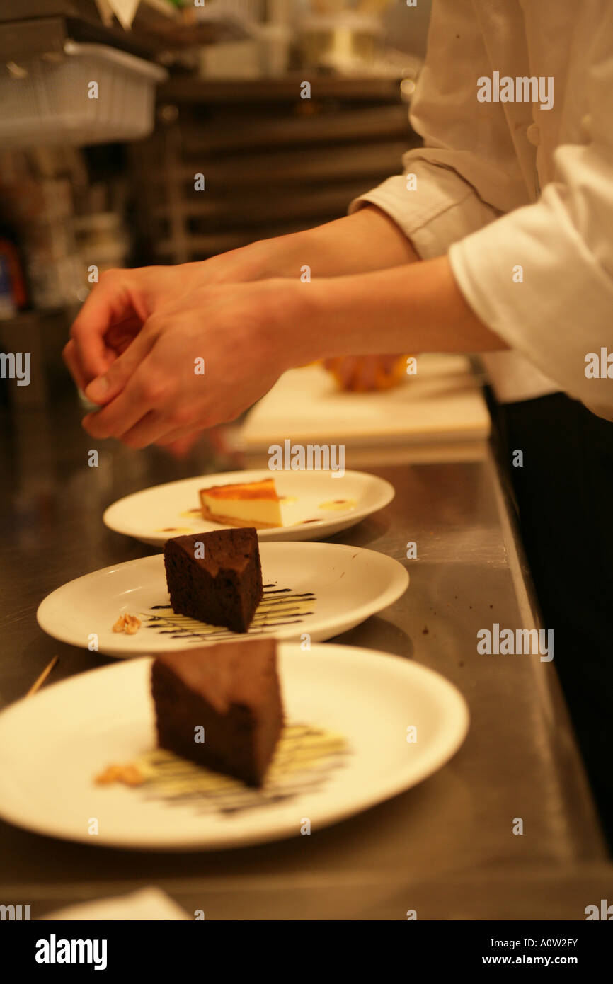 Mid section view of a female chef s hands over a plate of chocolate cake Stock Photo