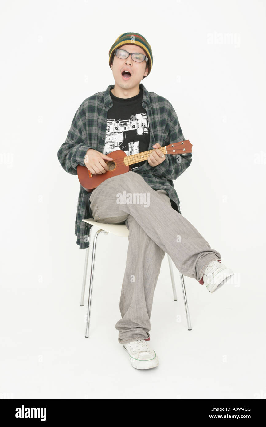 Portrait of a young man sitting on a chair and playing the guitar Stock ...