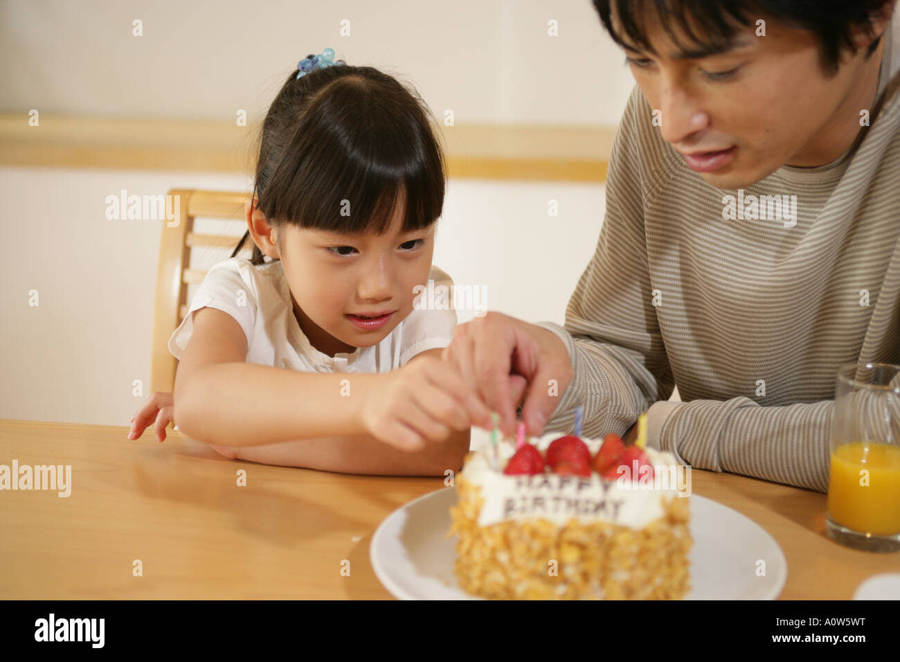 Mid adult man and his daughter putting candles on a birthday cake Stock Photo Alamy