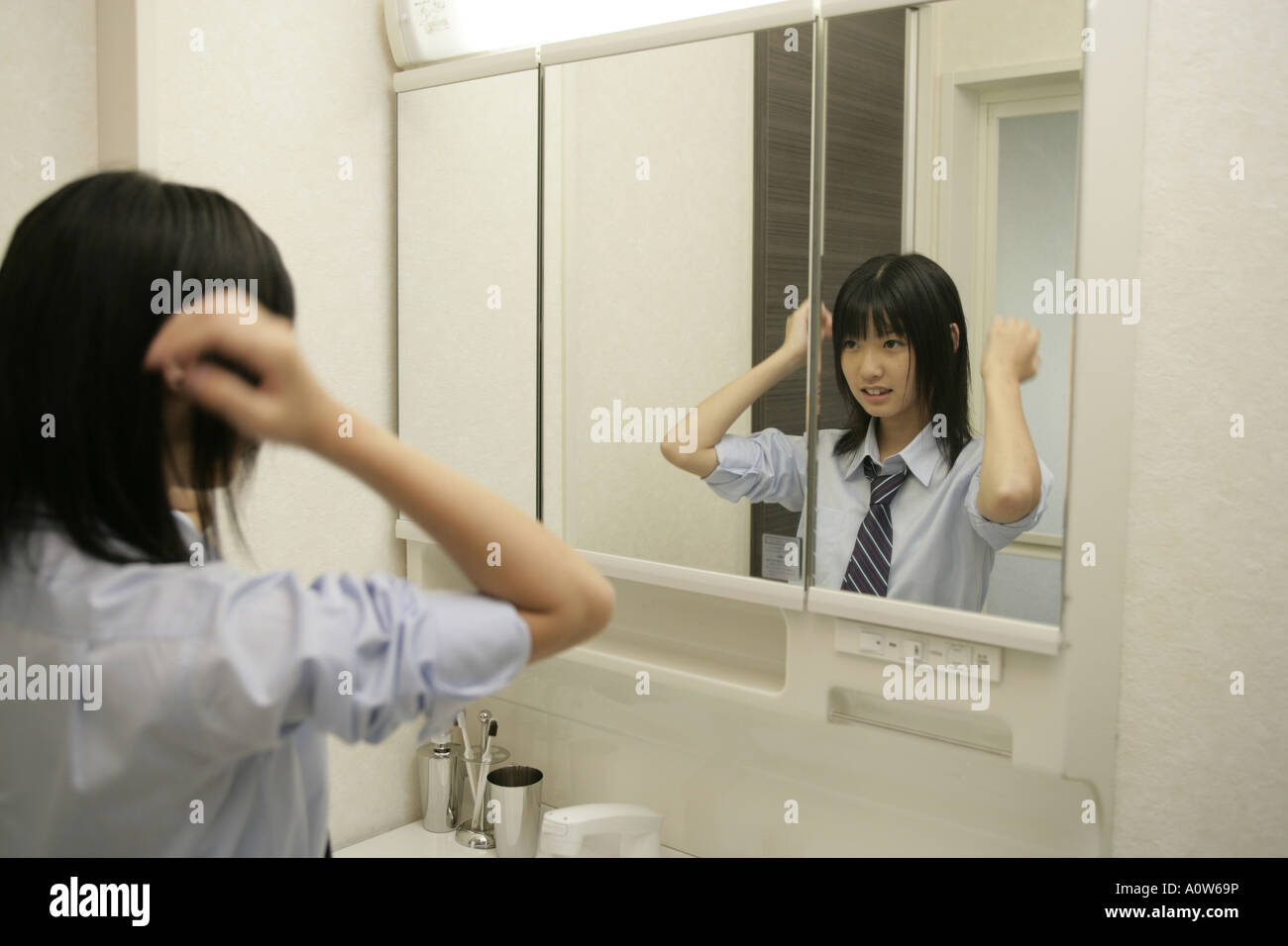 Teenage girl looking at herself in the mirror Stock Photo - Alamy