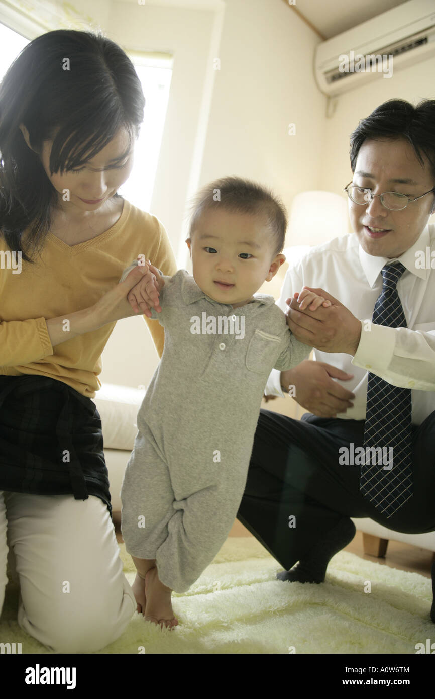 Mid adult couple helping their baby boy stand Stock Photo Alamy