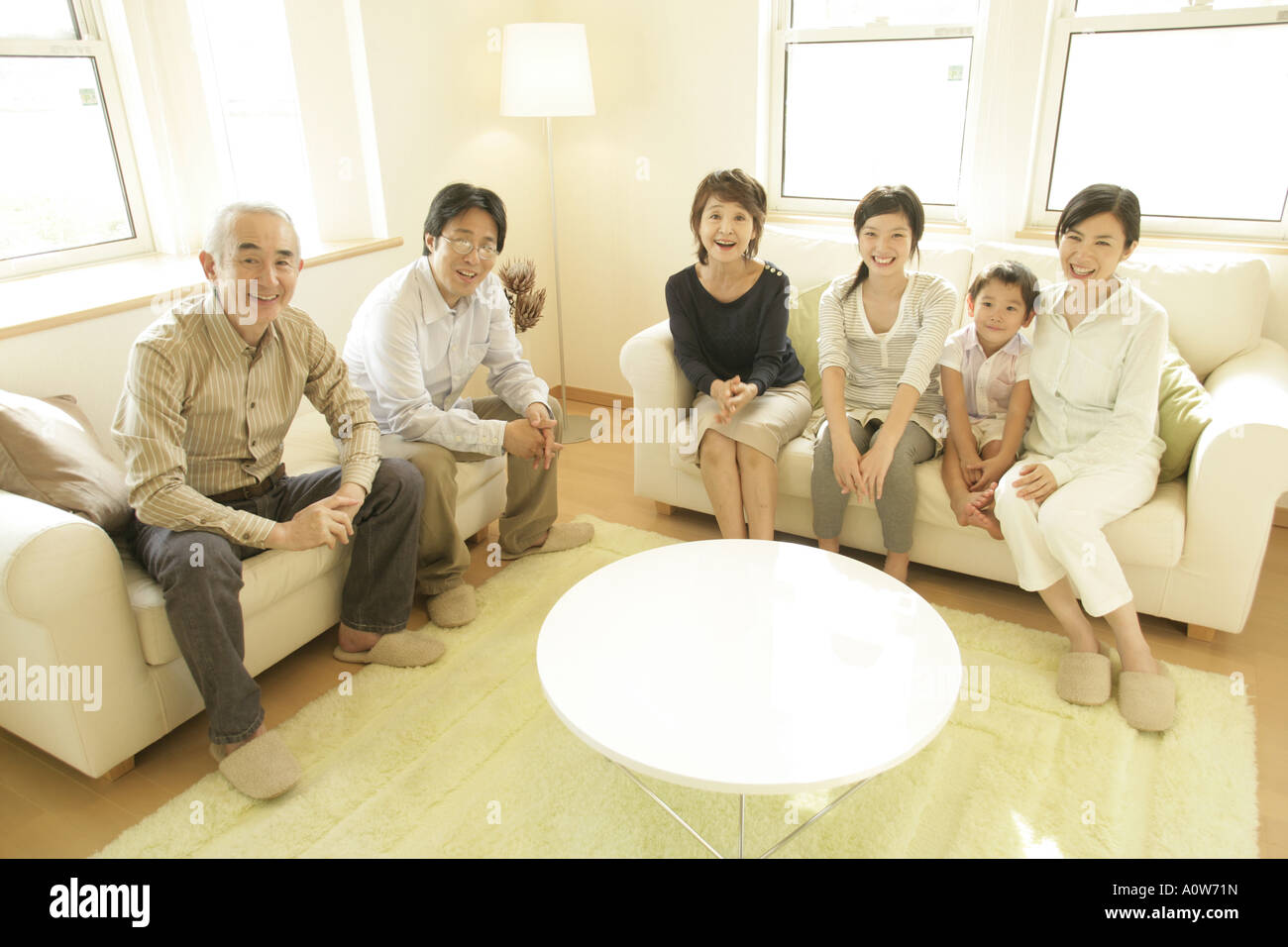 Portrait of a three generation family sitting in a living room and smiling Stock Photo