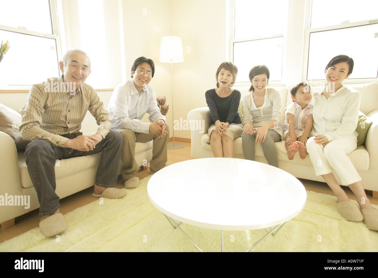 Portrait of a three generation family sitting in a living room and smiling Stock Photo