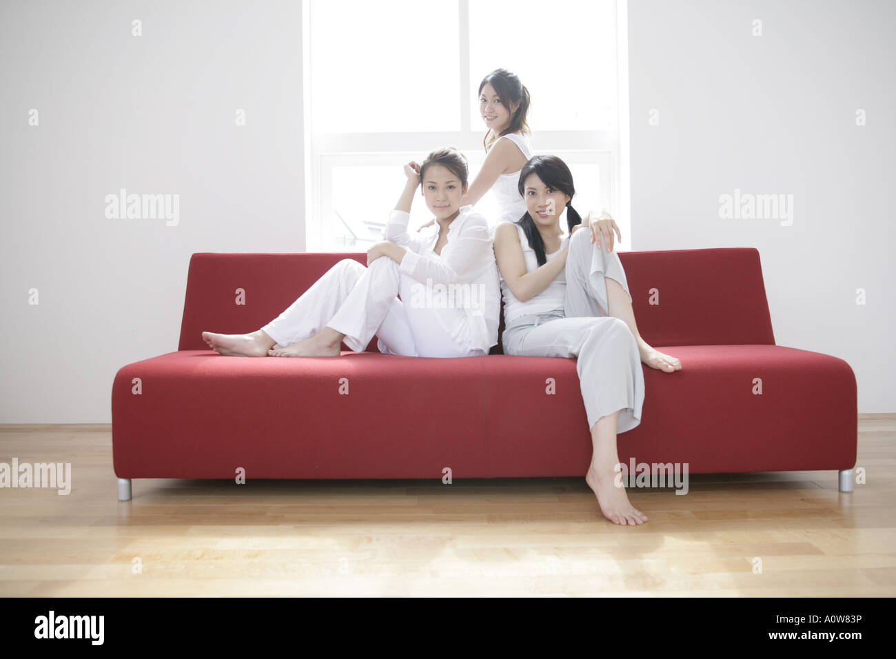 Portrait of three young women sitting on a couch and smiling Stock ...