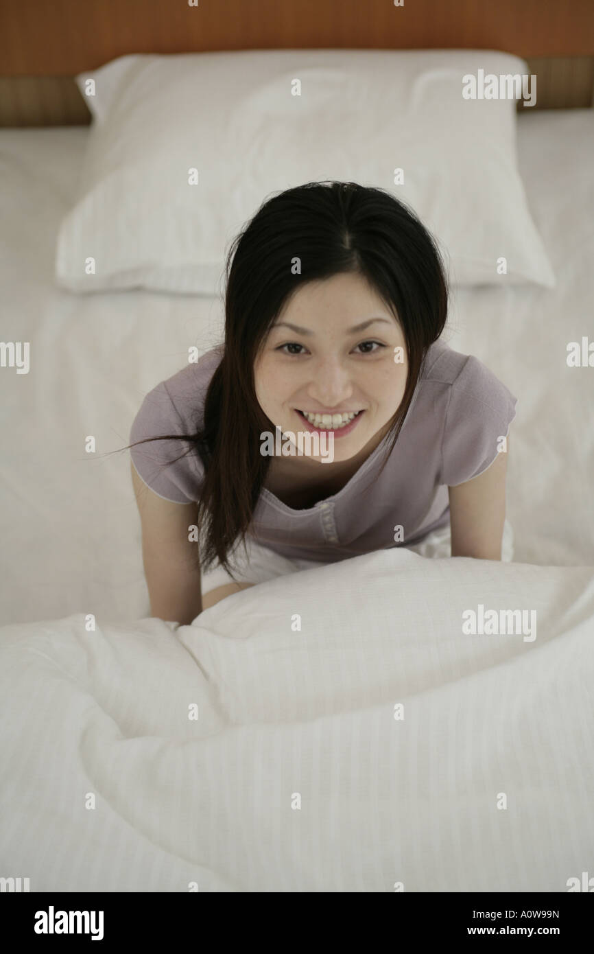 Portrait of a young woman sitting on the bed and smiling Stock Photo ...