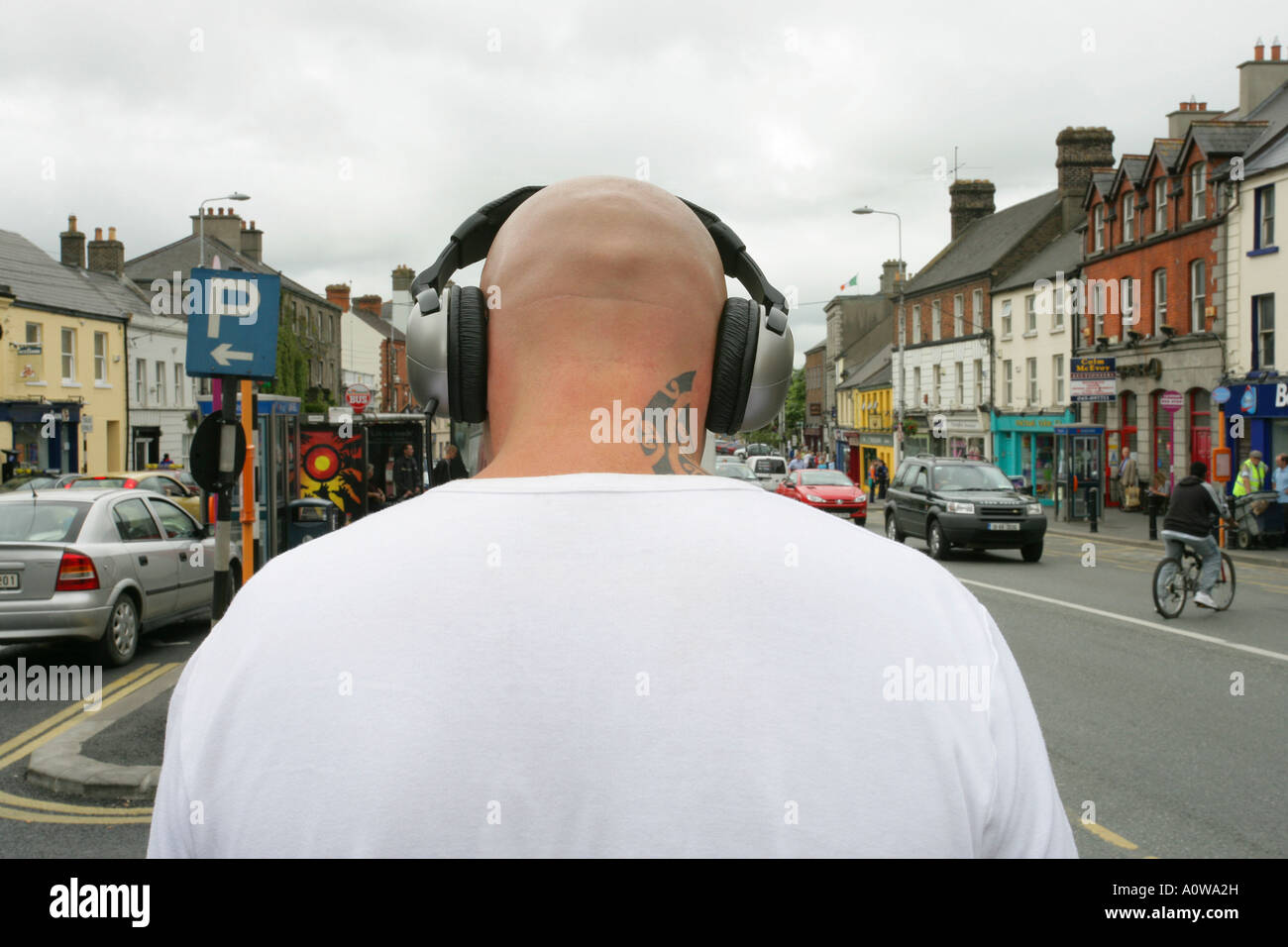 rear view of man with shaved head and tattoo wearing headphones Stock Photo