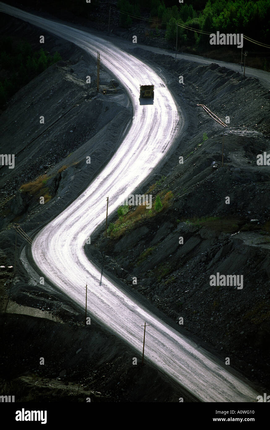 A truck climbs out of a pit asbestos mine on a curving utility road