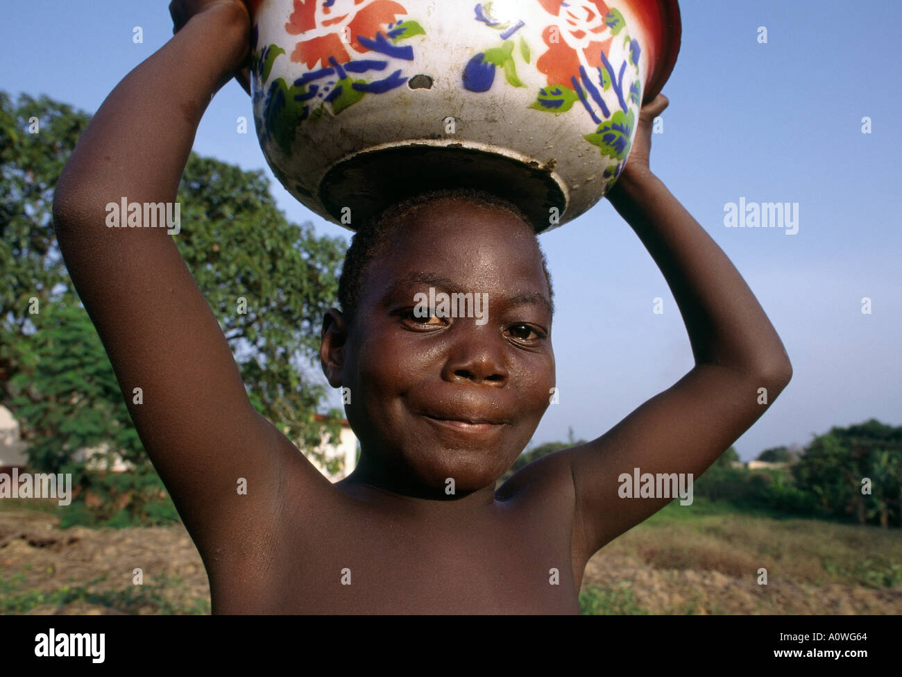 A young Liberian boy carries water home from a central well. Stock Photo