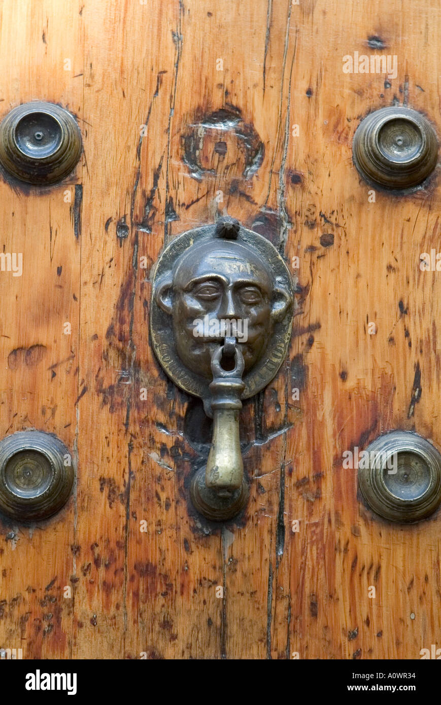 Old door knocker of a man s head on a large engraved wooden door in Mexico City Stock Photo
