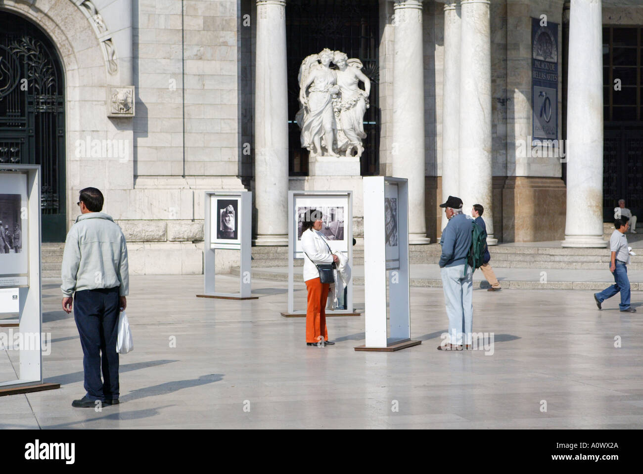 People viewing a photographic exhibition outside the Palace of Fine Arts in Mexico City Stock Photo