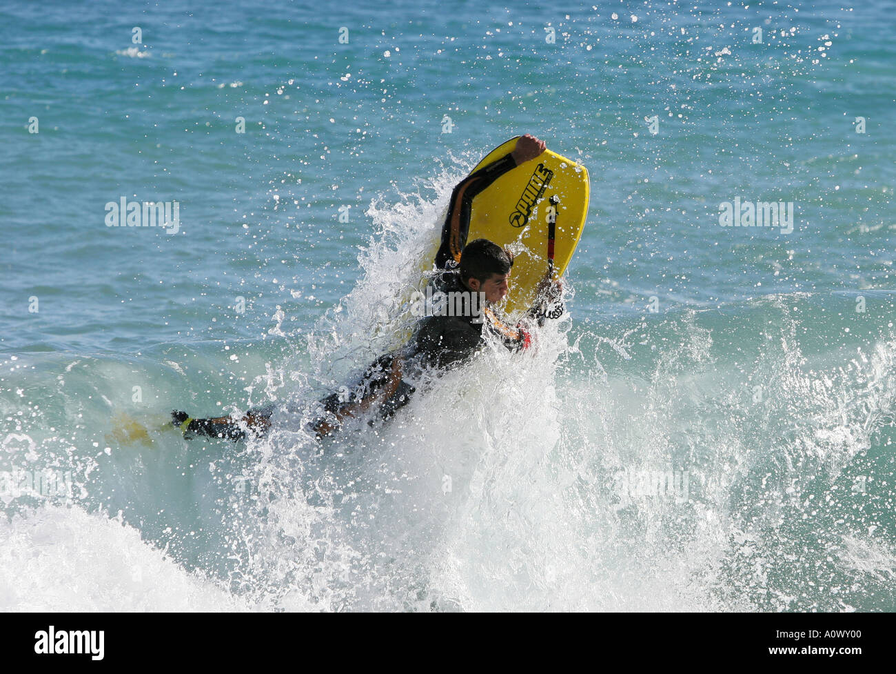 Boogie or body boarder hitting wave and flying out of deep blue water in Spain Blue sky blue sea and having fun Stock Photo