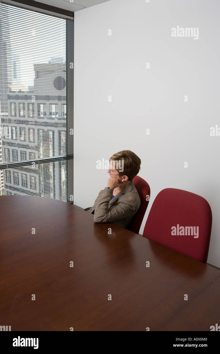 female business executive ponders over workload at office conference room Stock Photo