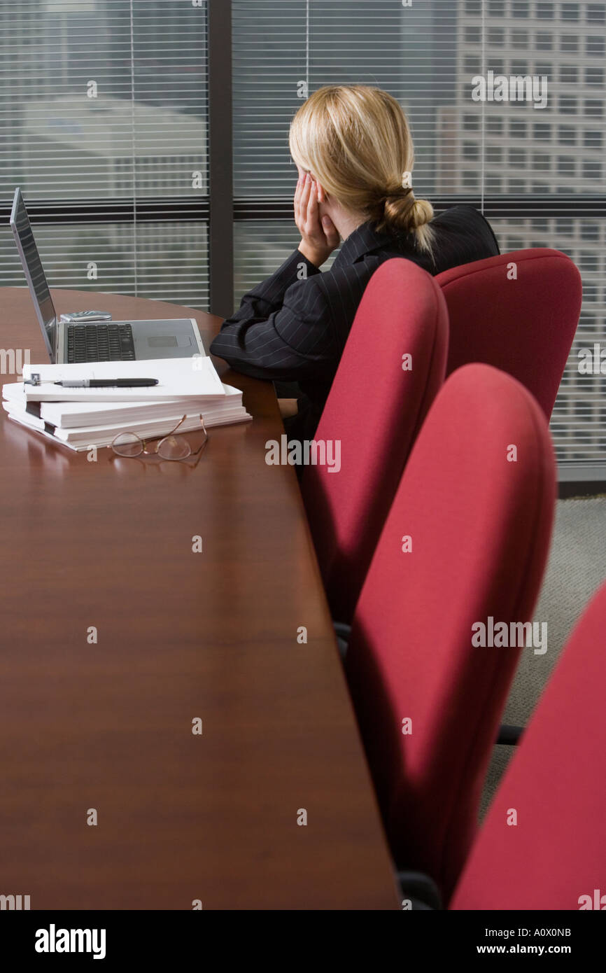 female executive office worker ponders over workload and paperwork in corporate conference room Stock Photo