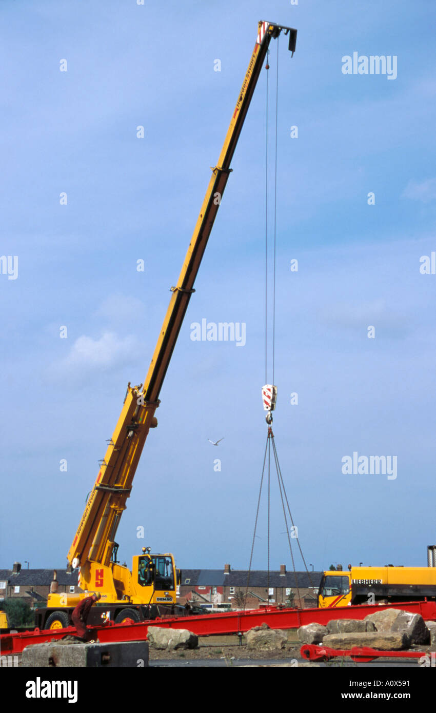 Mobile crane with an extending boom preparing to lift a section of