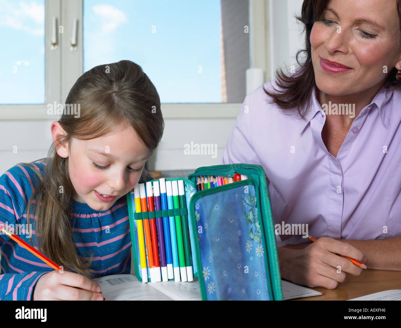 Mother watching daughter do homework Stock Photo - Alamy