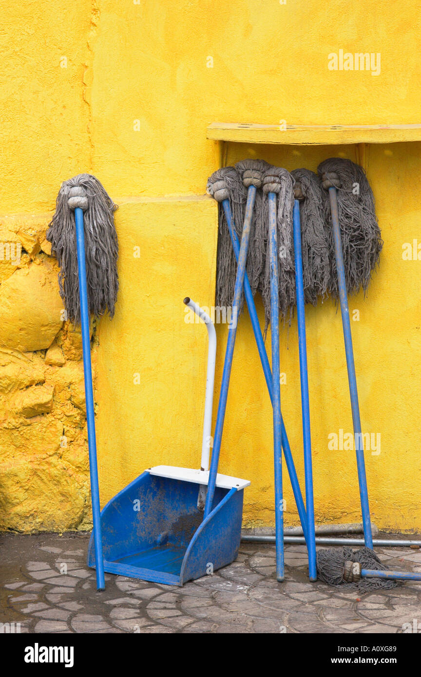 Blue handled mops and yellow wall outside restaurant on Malecon Kino