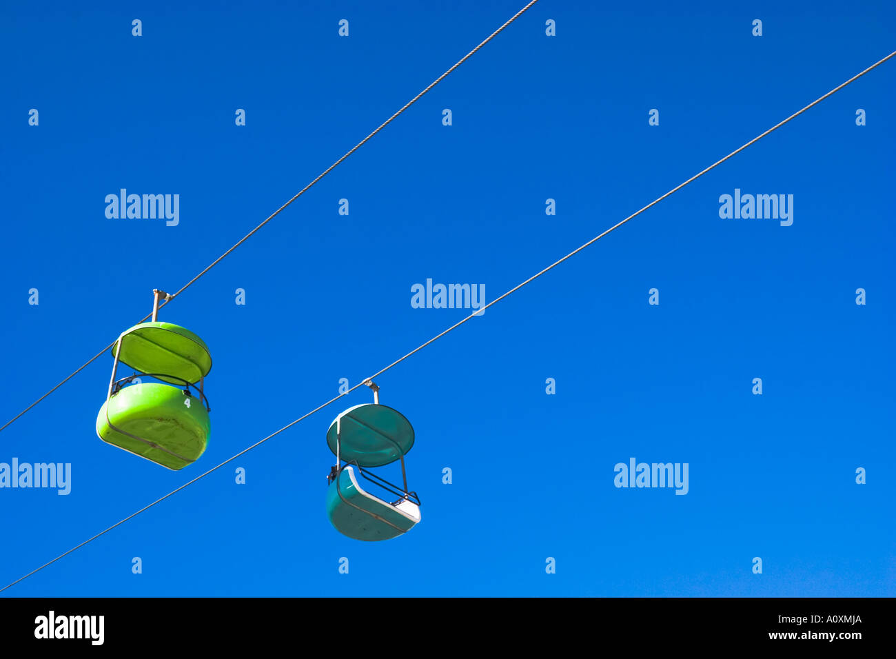 empty amusement park ride on cables against blue sky Stock Photo - Alamy