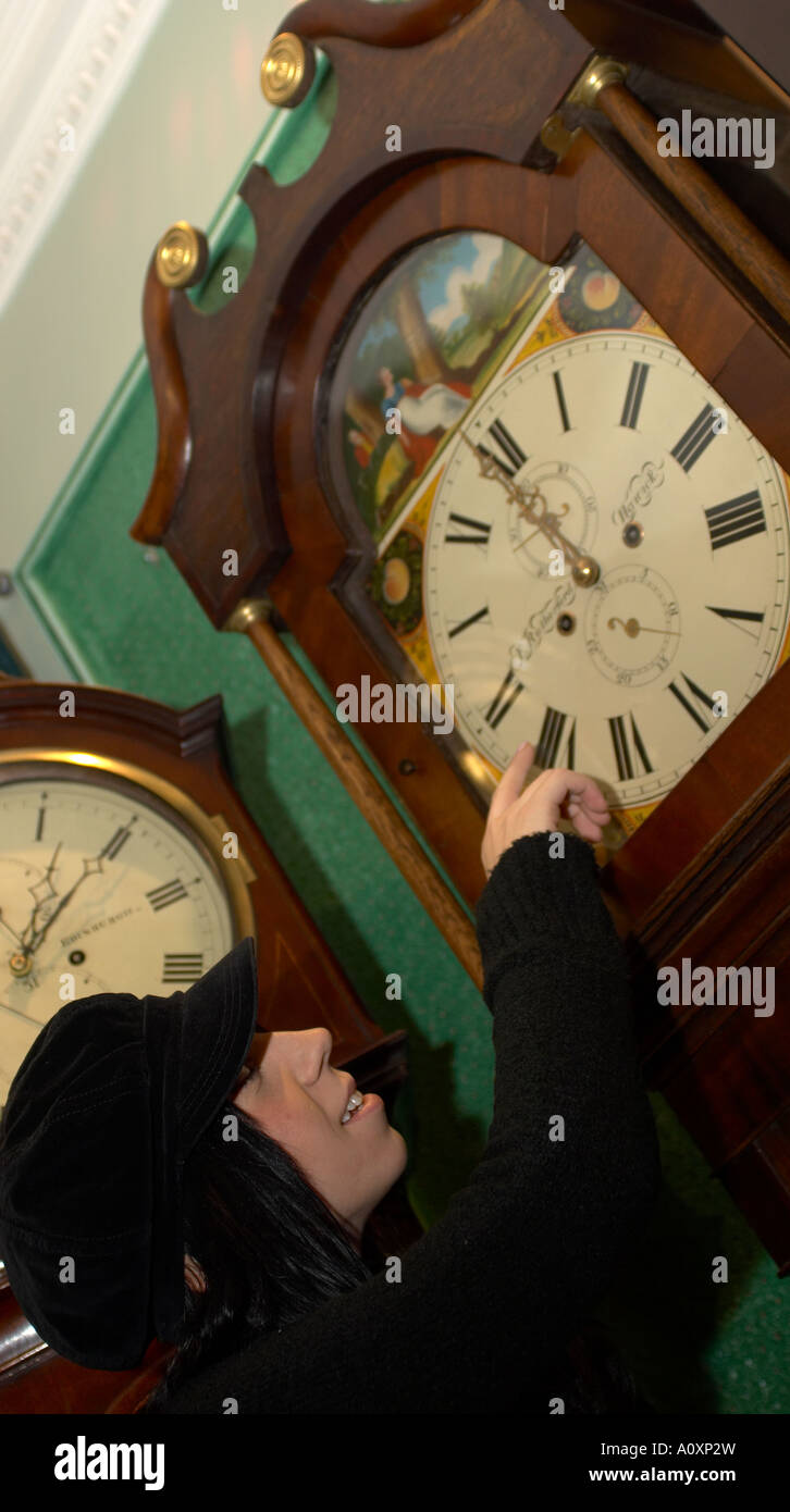 Young woman pointing at the time on a grandfather clock Stock Photo