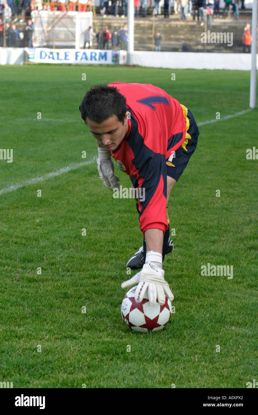 Northern Ireland goalkeeper 1 Jonathan Tuffy in red shirt bends down to