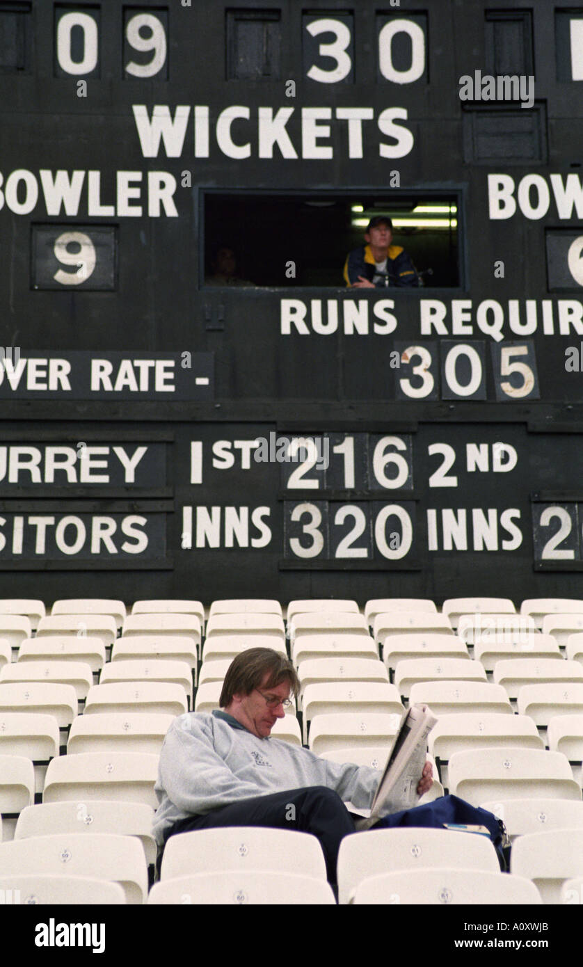 UK ENGLAND LONDON Spectator reading newspaper at a County Cricket match held at The Oval. Empty seats all around Stock Photo