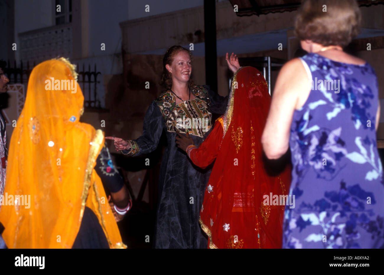 Indian dancing girls performs a traditional dance routine and are joined by western women on the dance floor Stock Photo