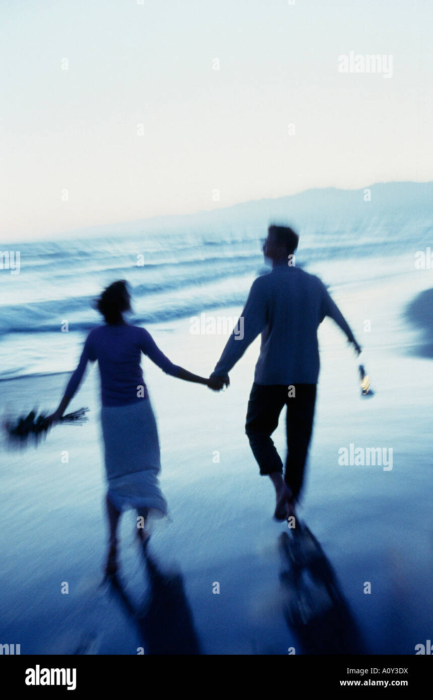 Rear view of a mid adult couple walking on the beach Stock Photo - Alamy