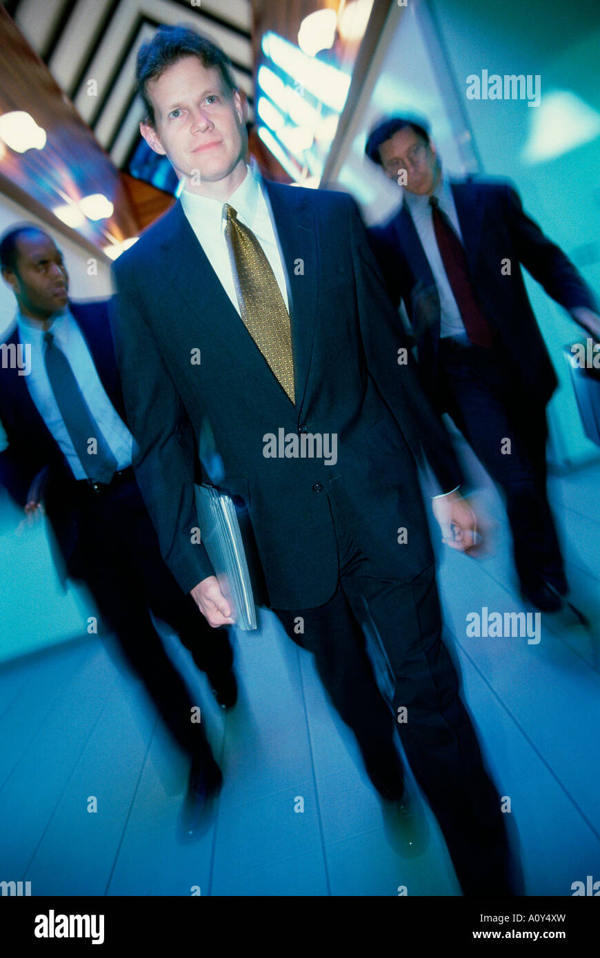 Three businessmen walking in a corridor Stock Photo - Alamy